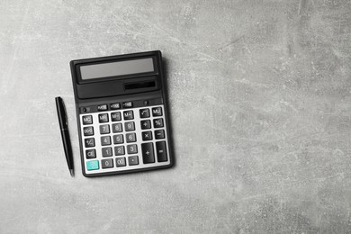 Calculator and pen on grey table, top view. Space for text