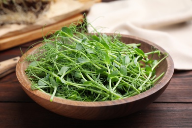 Photo of Plate with fresh microgreen on brown wooden table, closeup
