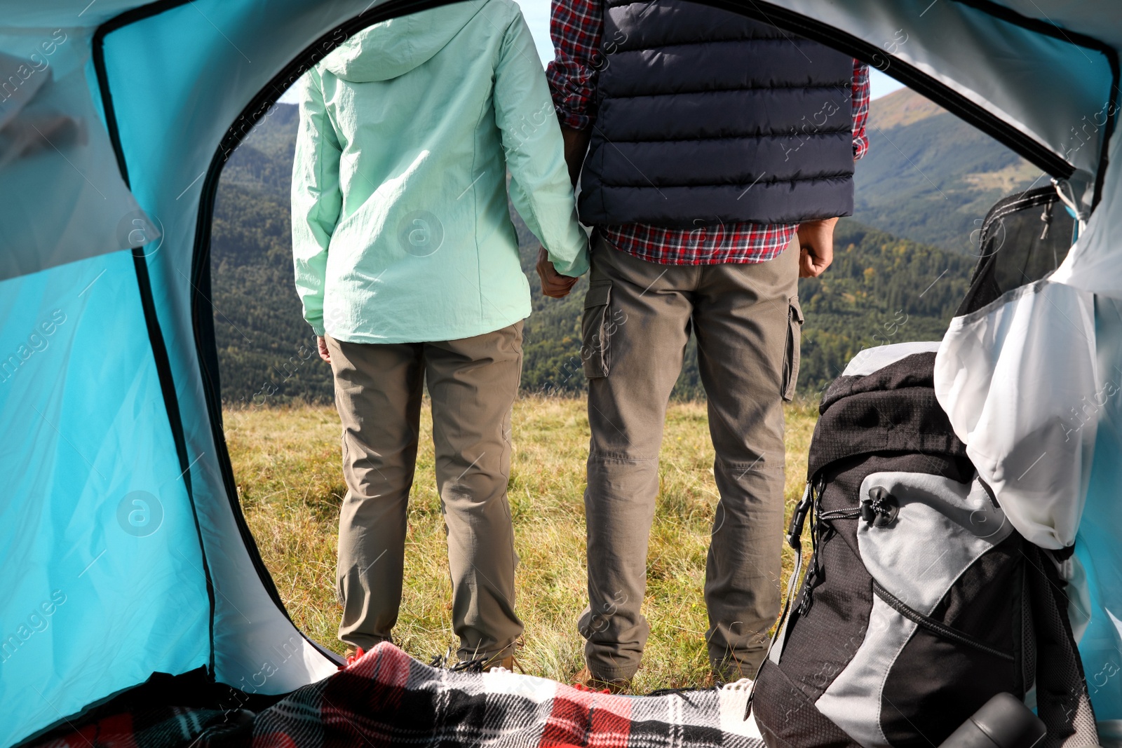 Photo of Couple in mountains on sunny day, view from camping tent