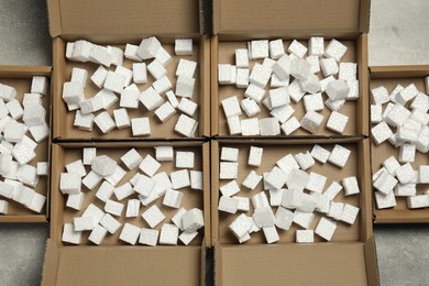 Many open cardboard boxes with pieces of polystyrene foam on grey textured background, flat lay