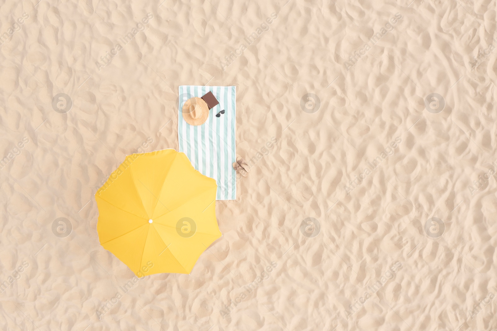 Image of Beach umbrella near towel and other vacationist's stuff on sand, aerial view. Space for text