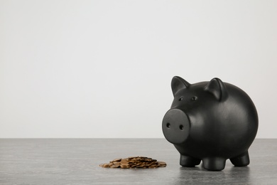 Photo of Piggy bank and coins on table against white background. Space for text