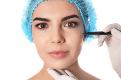 Doctor holding marker near young woman's face isolated on white, closeup. Plastic surgery concept
