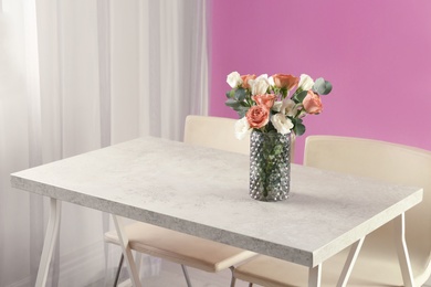 Vase with beautiful flowers as element of interior design on table in room. Space for text