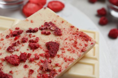 Chocolate bars with freeze dried raspberries on light marble board, closeup