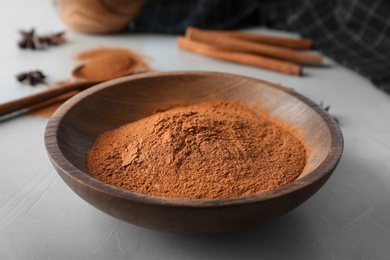 Bowl with aromatic cinnamon powder on table