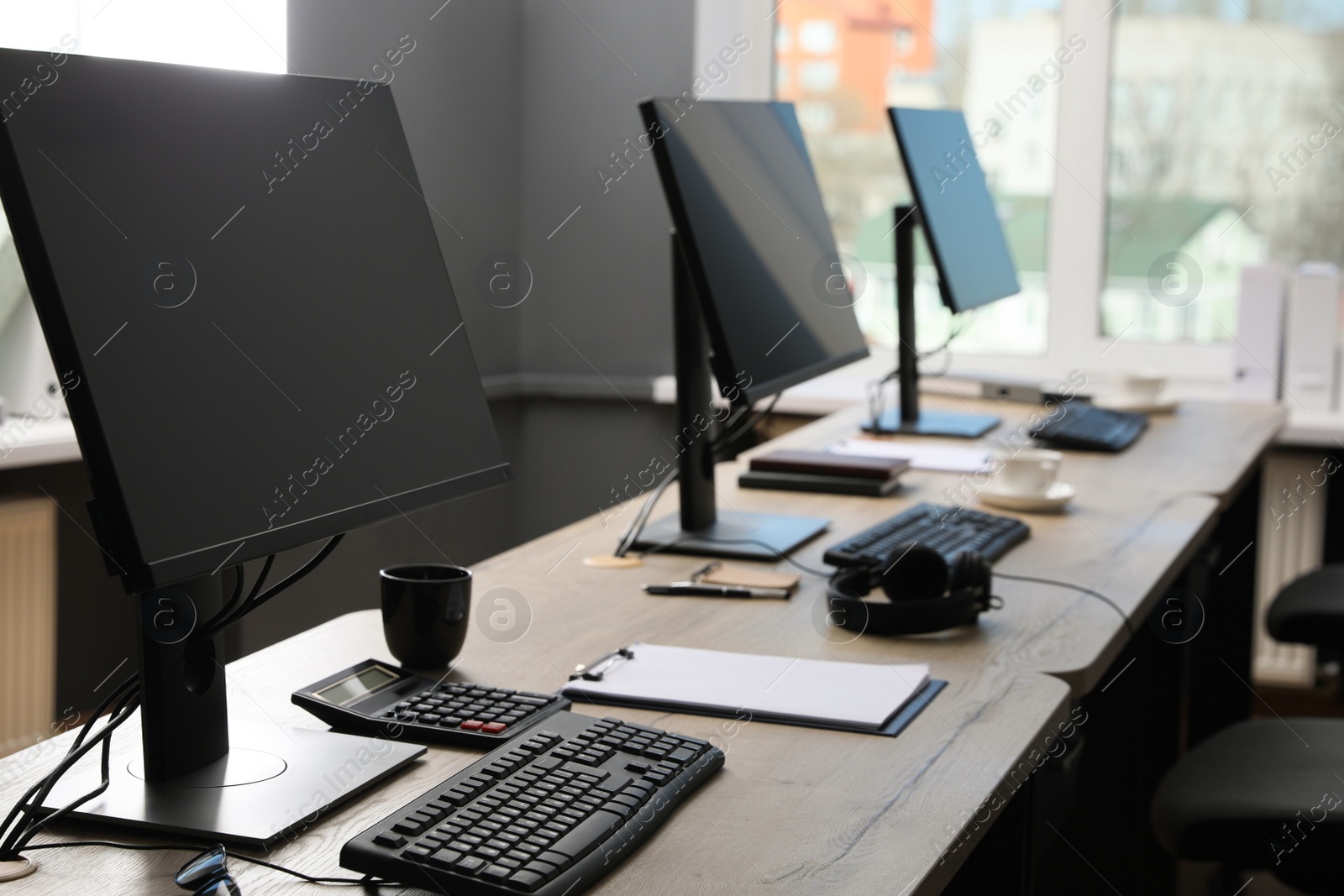Photo of Open office interior. Modern workplaces with computers near window