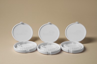 Photo of Containers with dental mouth guards on beige background. Bite correction