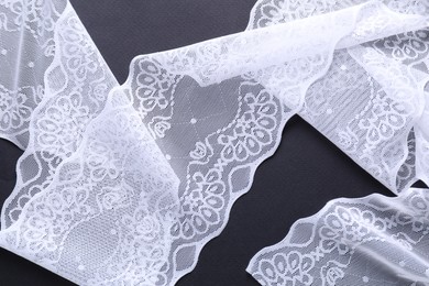 Photo of White lace on black background, top view