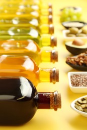 Vegetable fats. Different oils in glass bottles and ingredients on yellow table, closeup