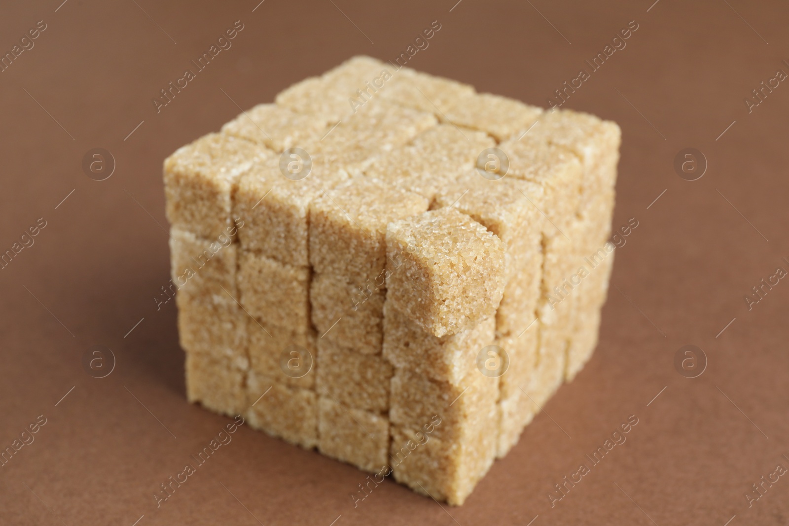 Photo of Brown sugar cubes on color background, closeup