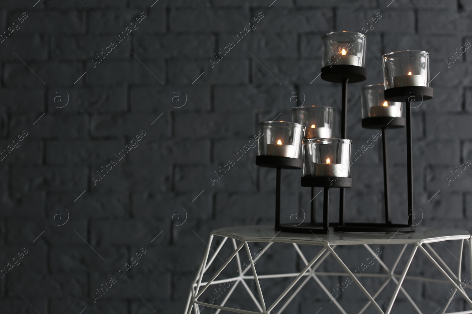 Photo of Burning candles on table near brick wall