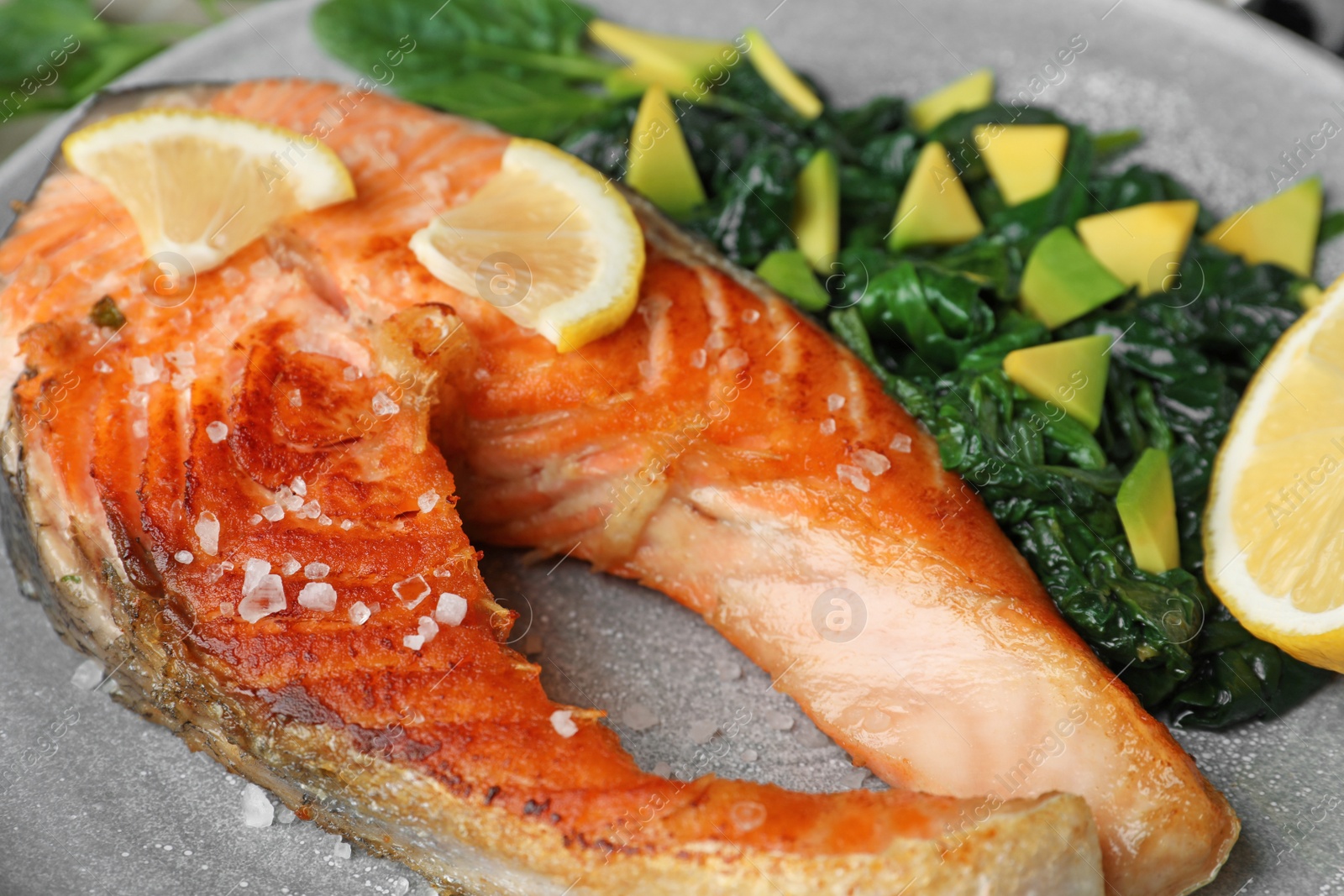 Photo of Tasty salmon with spinach on plate, closeup