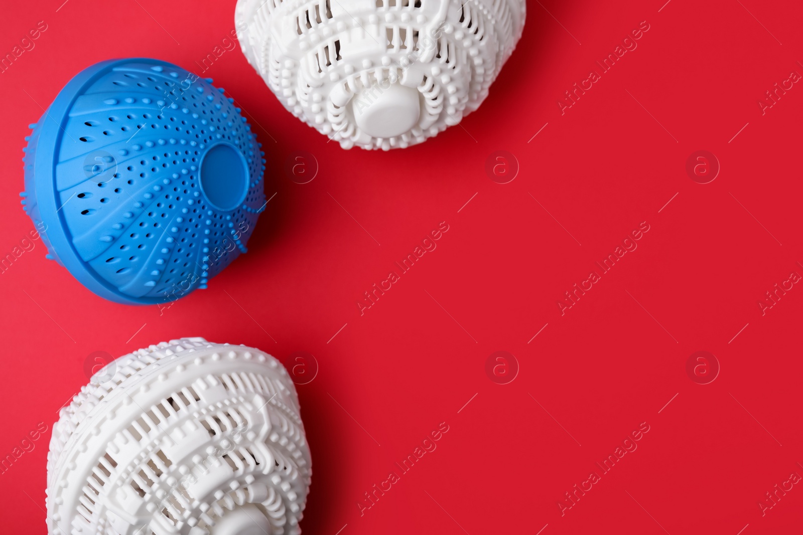 Photo of Laundry dryer balls on red background, flat lay. Space for text
