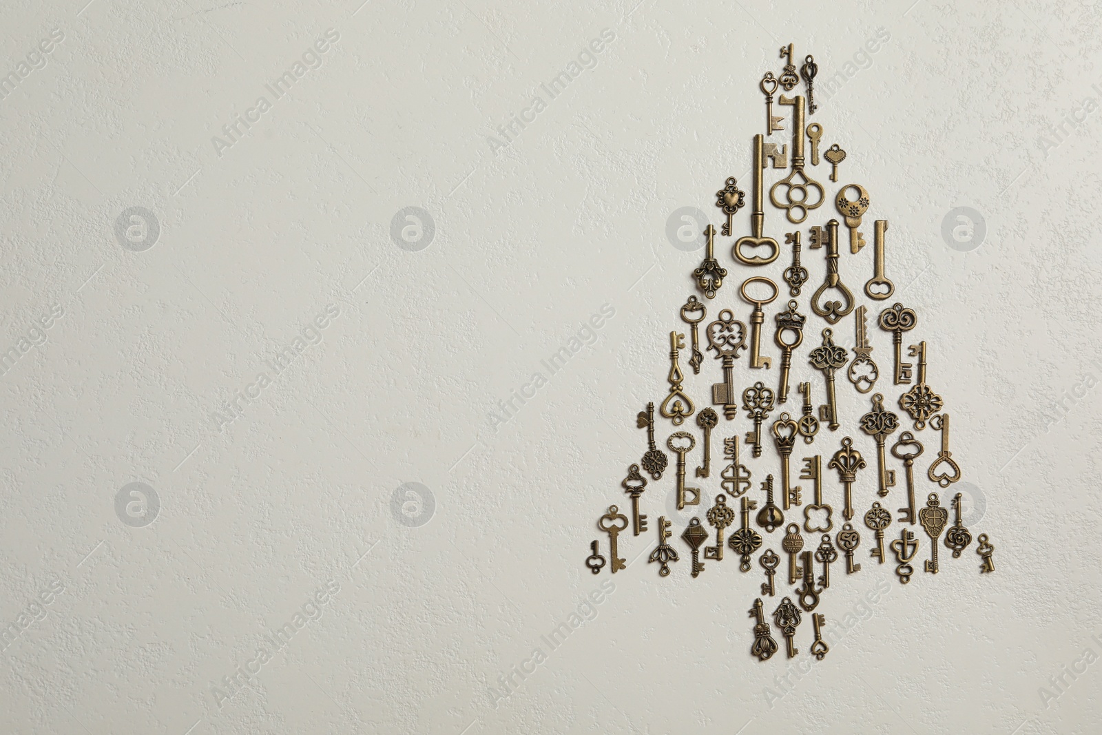 Photo of Flat lay composition with Christmas tree made of keys on light background, space for text