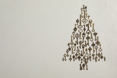 Photo of Flat lay composition with Christmas tree made of keys on light background, space for text