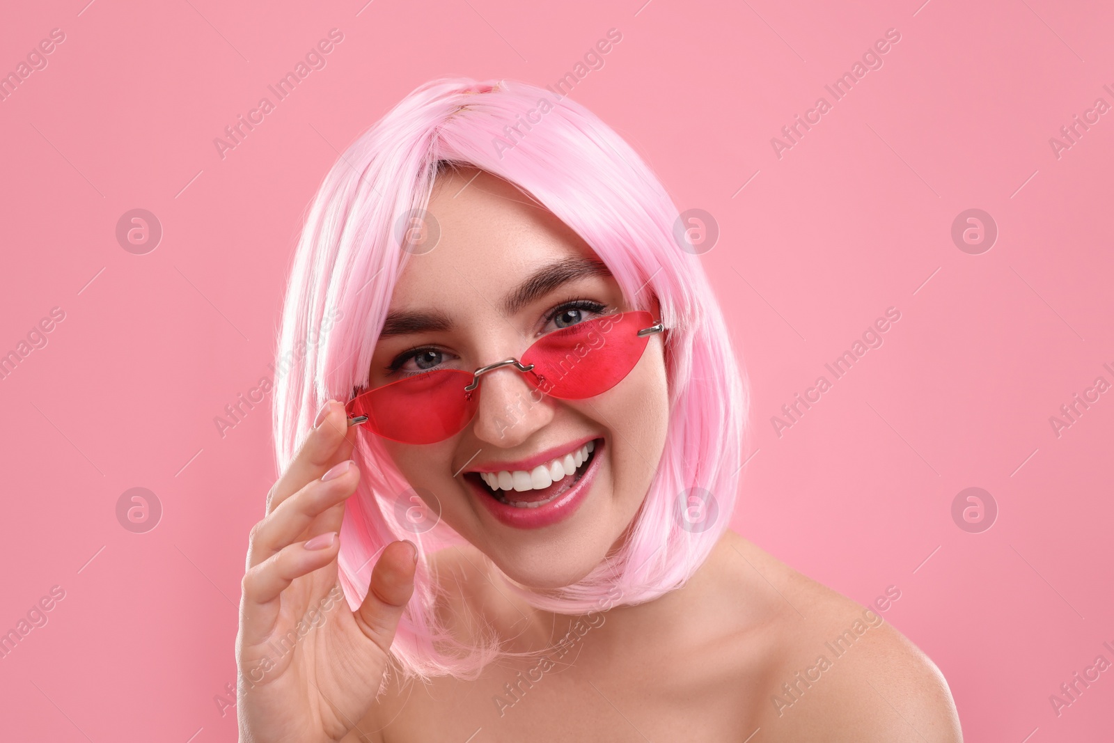 Photo of Pink look. Beautiful girl in wig and bright sunglasses on color background