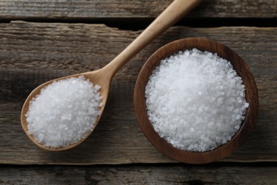 Photo of Organic salt in bowl and spoon on wooden table, flat lay