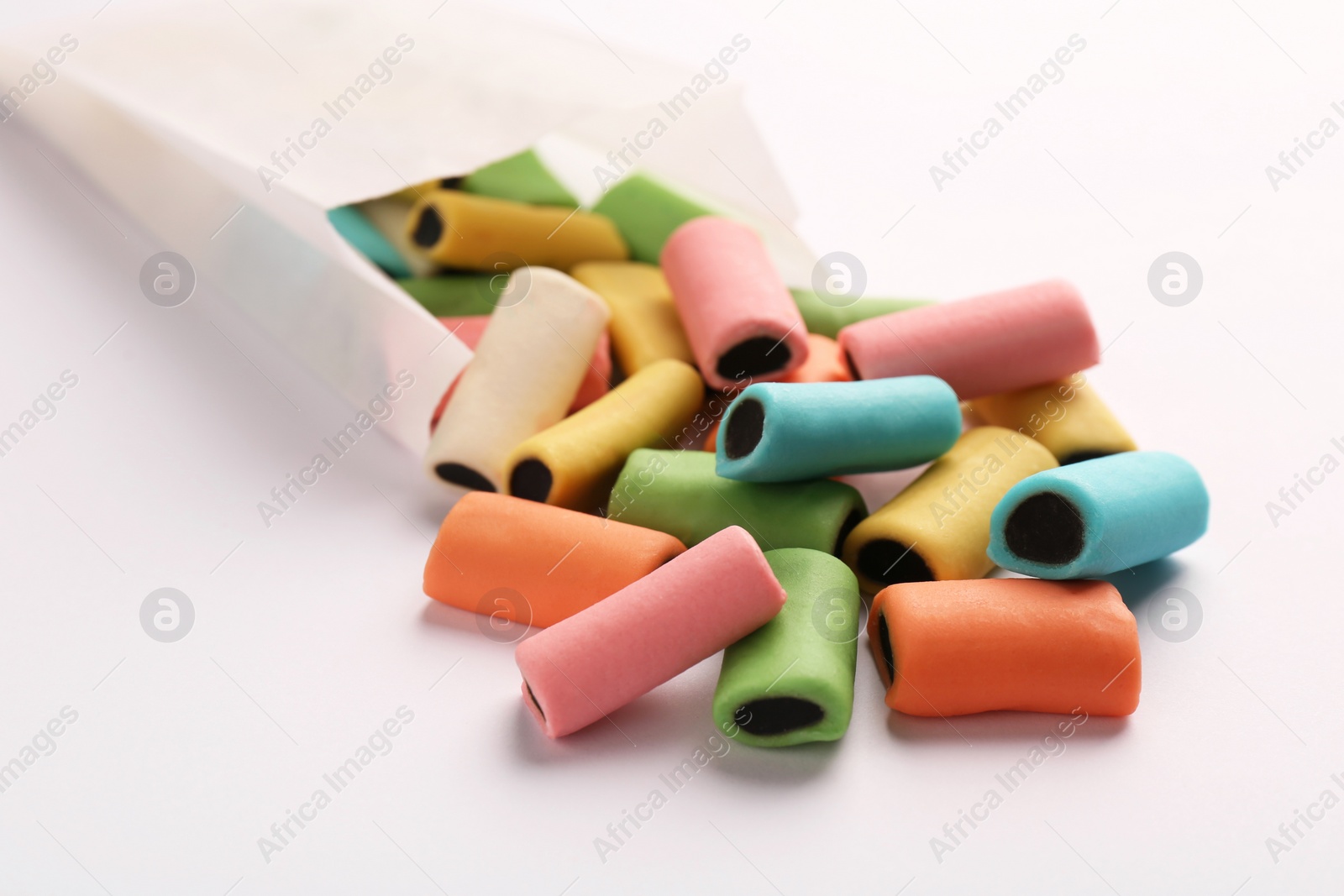 Photo of Paper bag with tasty liquorice candies on light background, closeup