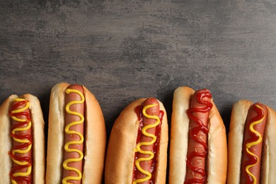 Photo of Delicious hot dogs with mustard and ketchup on grey table, flat lay. Space for text