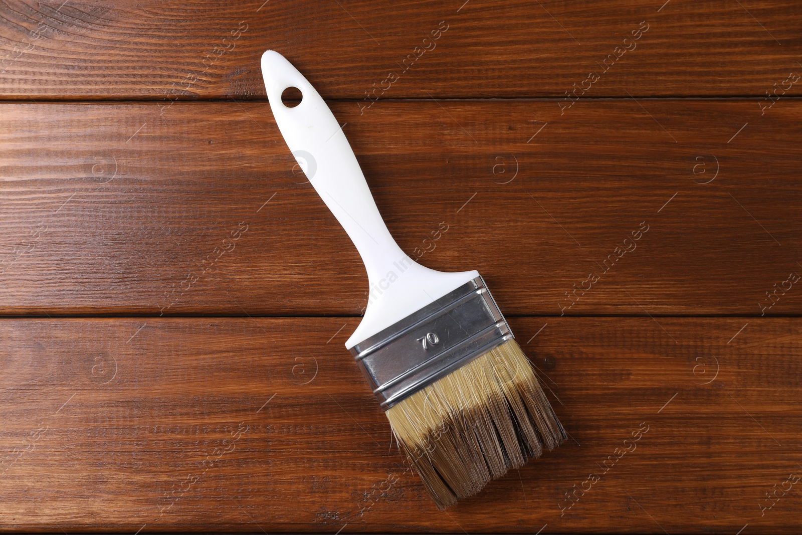 Photo of Brush with wood stain on wooden surface, top view