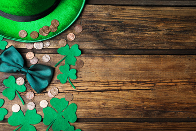 Photo of Flat lay composition with green leprechaun hat and clover leaves on wooden table, space for text. St. Patrick's Day celebration
