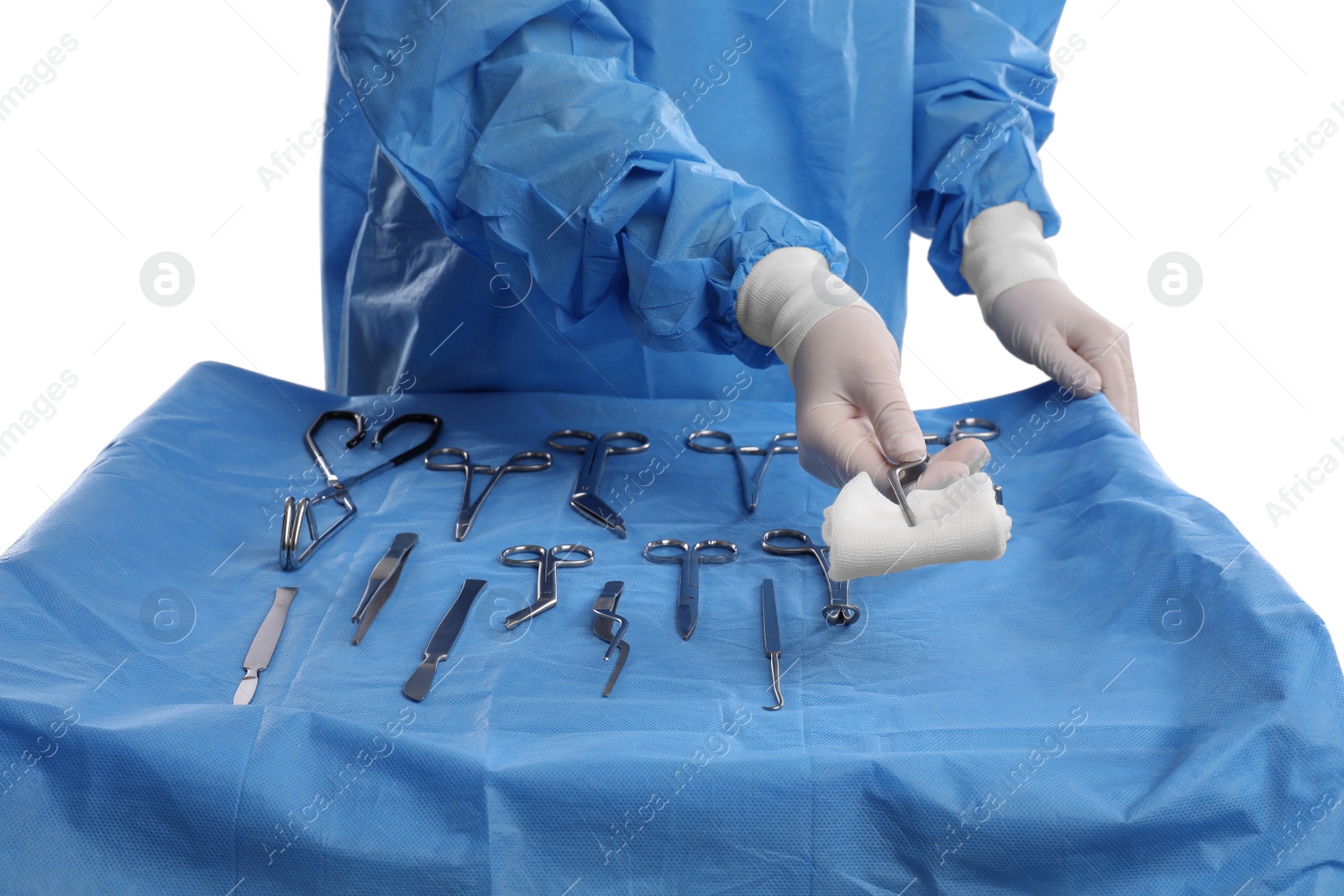 Photo of Doctor holding medical forceps with pad near table of different surgical instruments on light background, closeup