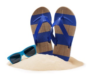 Photo of Striped flip flops in sand and sunglasses on white background
