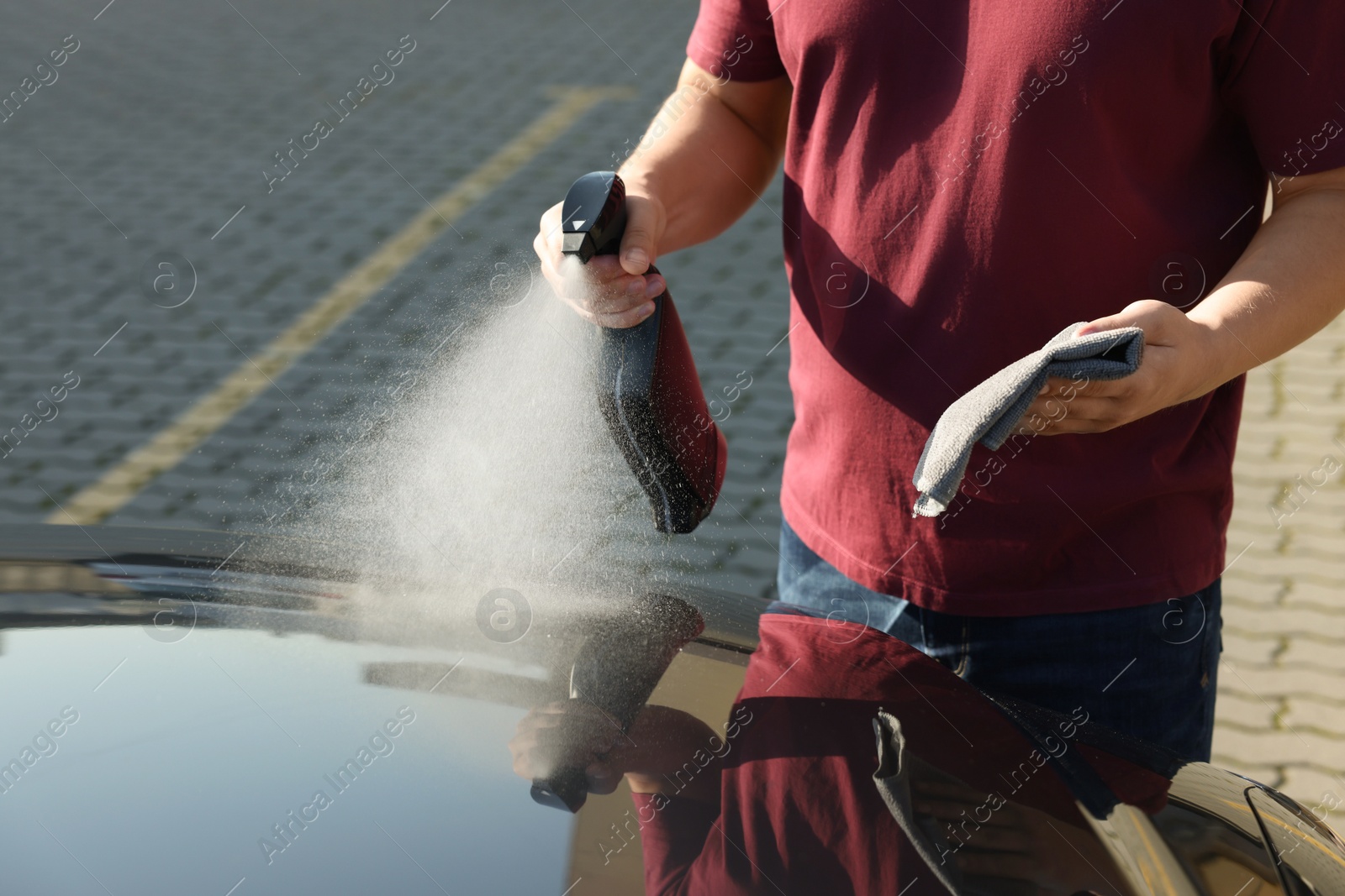 Photo of Man cleaning car hood outdoors, closeup view