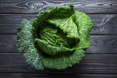 Photo of Fresh ripe savoy cabbage on black wooden table, top view