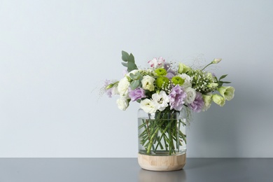 Photo of Bouquet with beautiful Eustoma flowers in vase on grey table against light background. Space for text