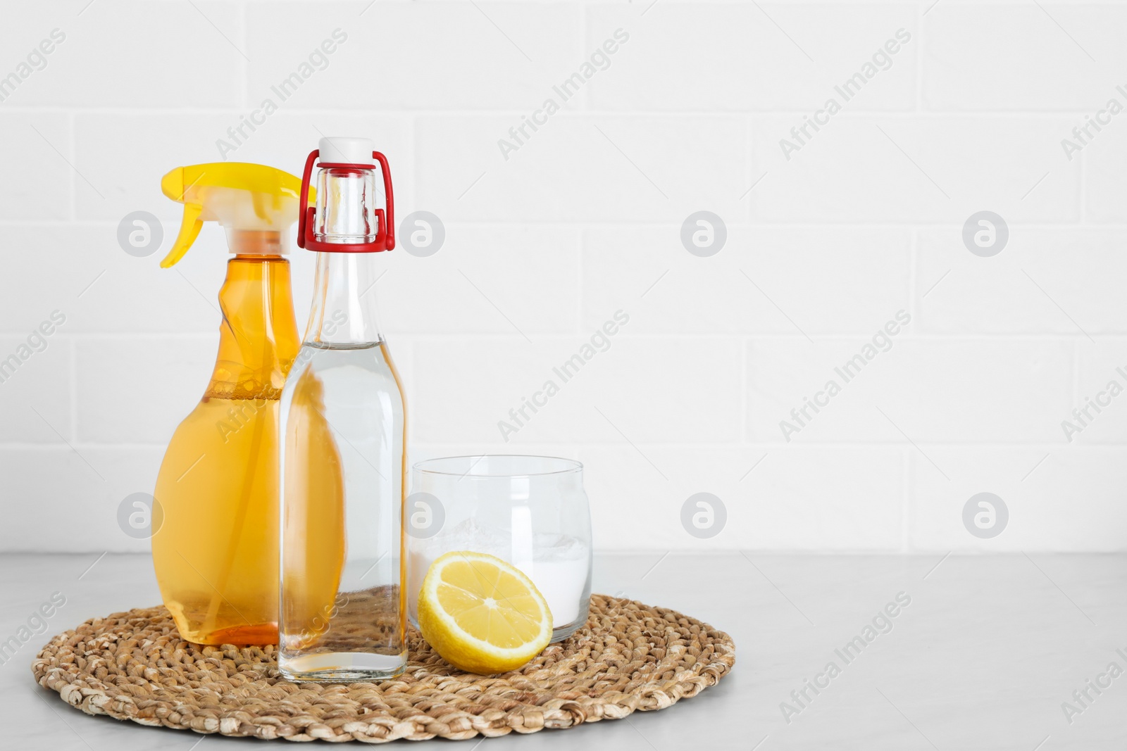 Photo of Vinegar, baking soda and lemon on white marble table, space for text. Eco friendly natural detergents