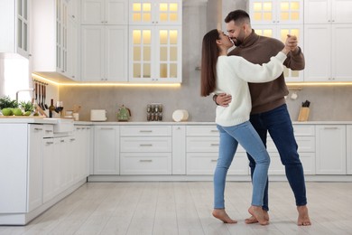 Affectionate young couple dancing and kissing in kitchen. Space for text