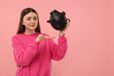 Photo of Sad woman with piggy bank on pink background, space for text