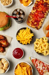 French fries, onion rings and other fast food on white wooden table, flat lay