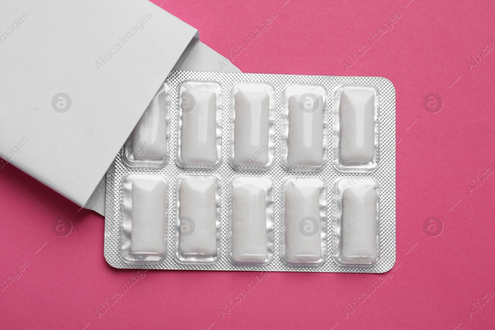 Photo of Pack with tasty chewing gums on bright pink background, top view