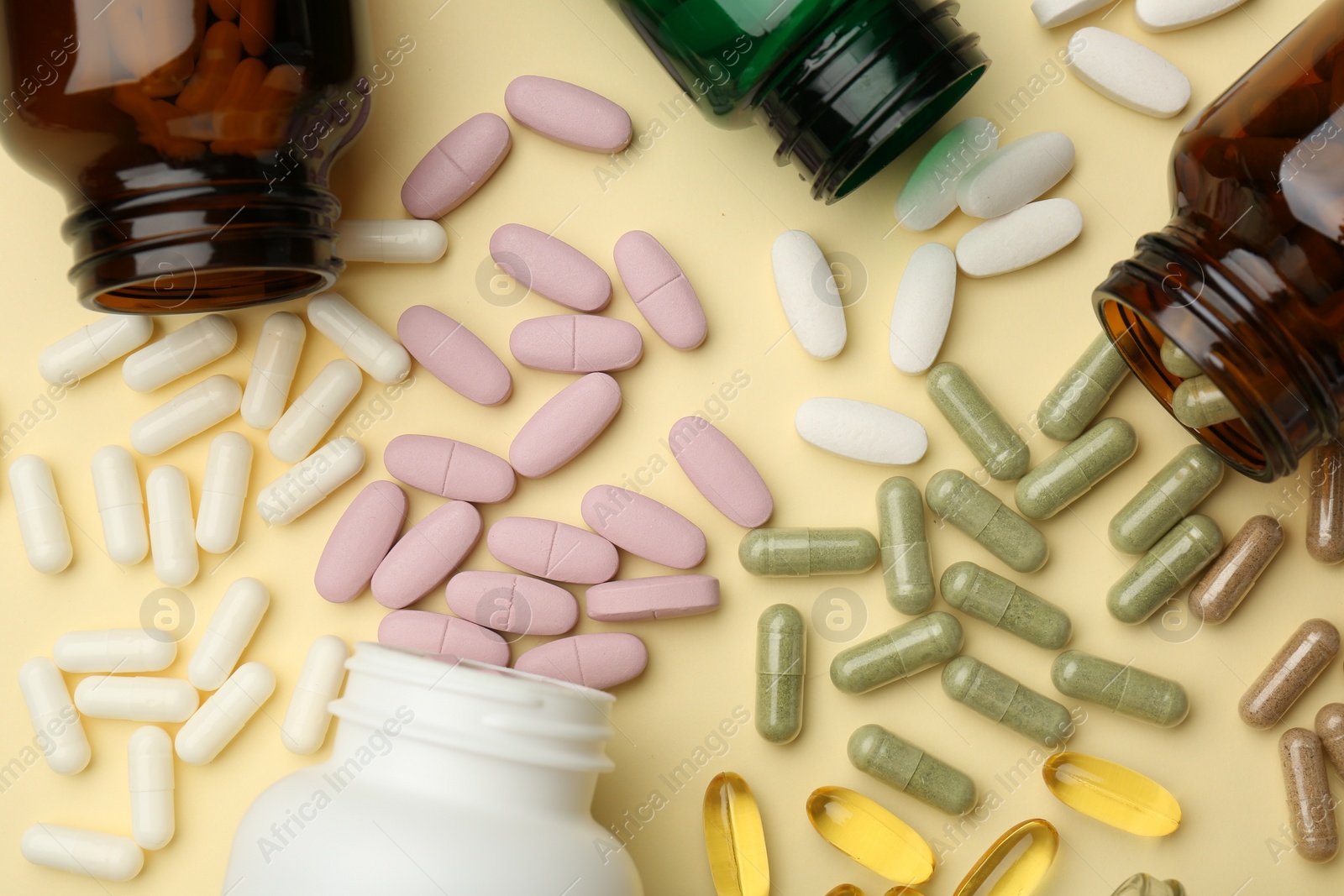 Photo of Many different vitamin pills and bottles on beige background, flat lay