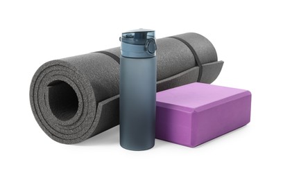 Grey exercise mat, yoga block and bottle of water isolated on white