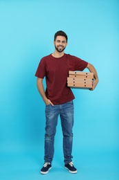 Young courier with pizza boxes on color background. Food delivery service