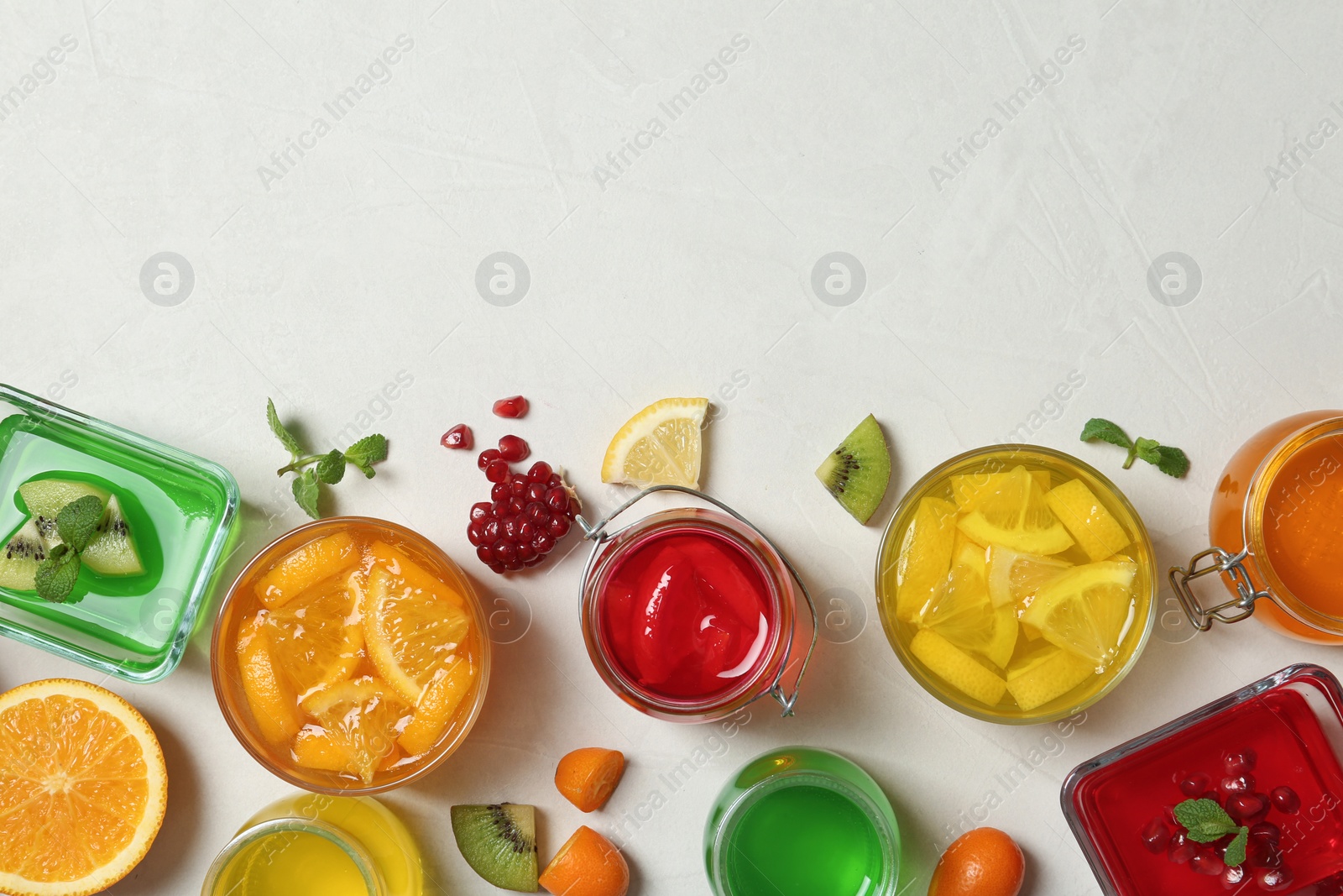 Photo of Flat lay composition with different jelly desserts on light background, space for text