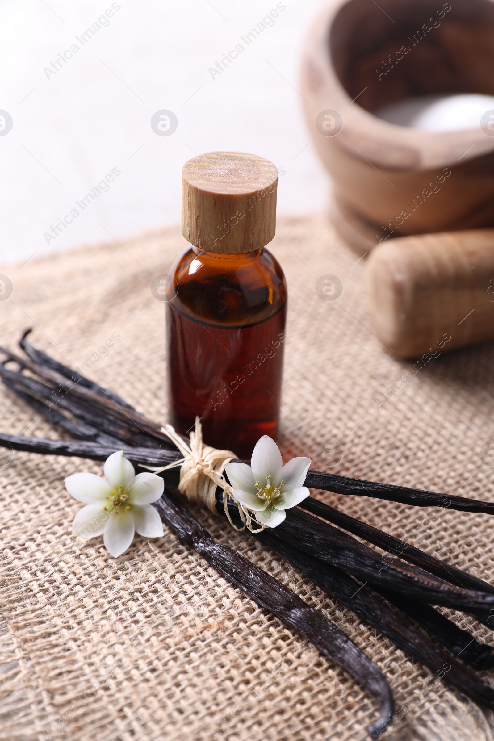 Photo of Vanilla pods, essential oil and flowers on table