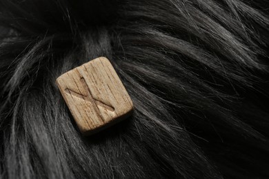 Photo of Wooden rune Nauthiz on grey faux fur, top view. Space for text
