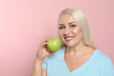 Photo of Smiling woman with perfect teeth and green apple on color background, space for text