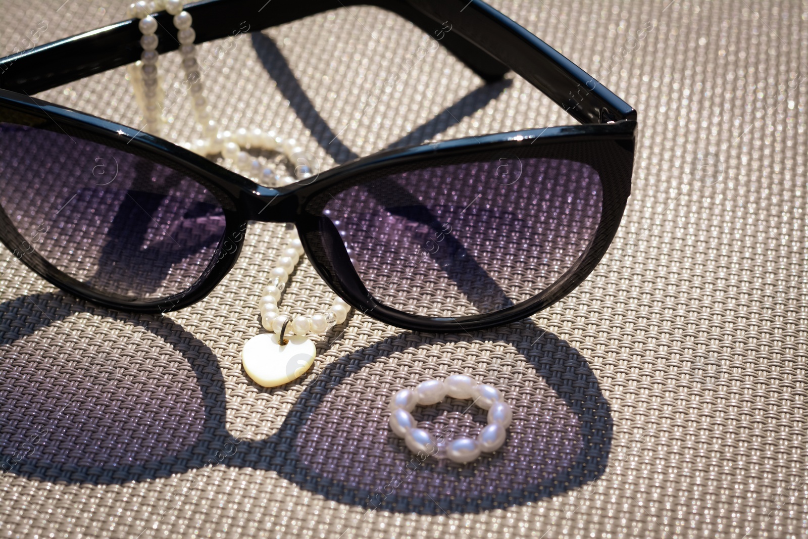 Photo of Stylish sunglasses and jewelry on grey surface, closeup