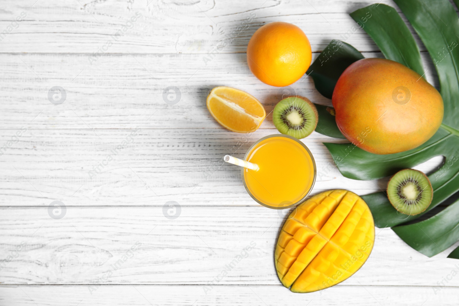 Photo of Glass of tasty mango juice and fresh fruits on wooden table, flat lay. Space for text