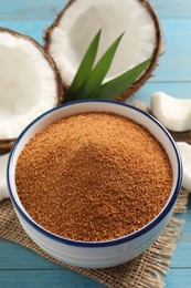 Natural coconut sugar in bowl on light blue wooden table