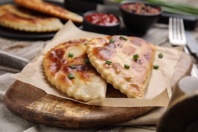 Delicious fried chebureki on wooden board, closeup