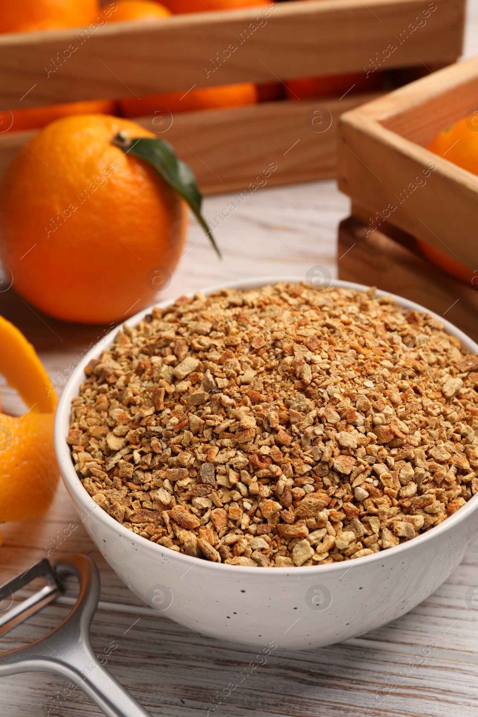 Photo of Bowl with dried orange seasoning zest and fruits on white wooden table, closeup