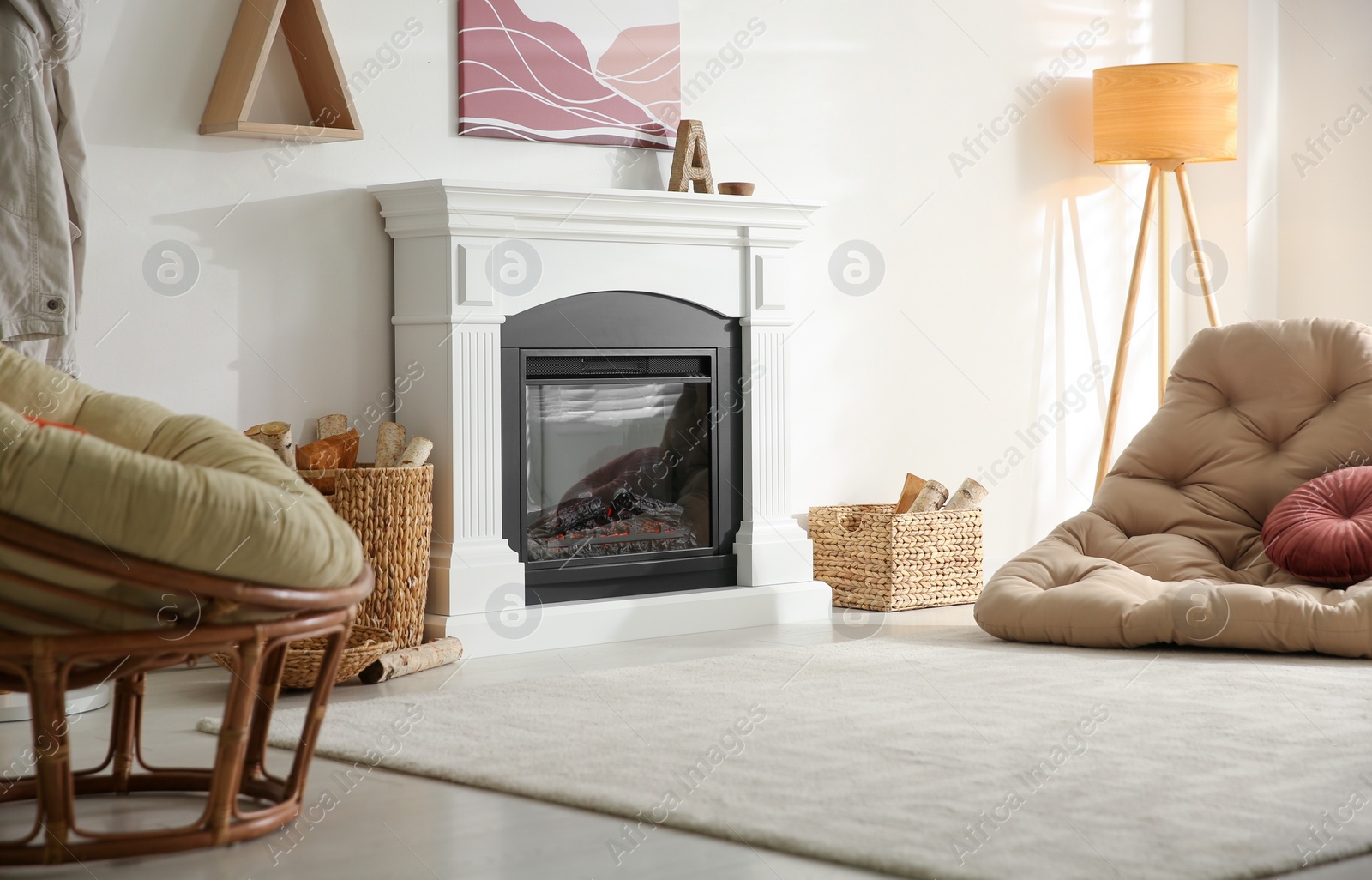 Photo of Bright living room interior with artificial fireplace and baskets of firewood