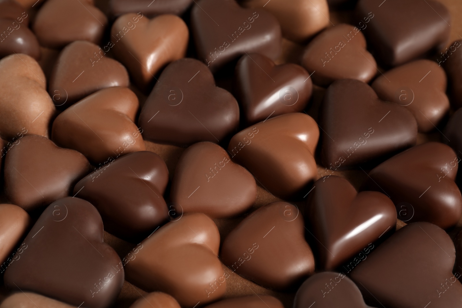 Photo of Beautiful heart shaped chocolate candies on brown background, closeup